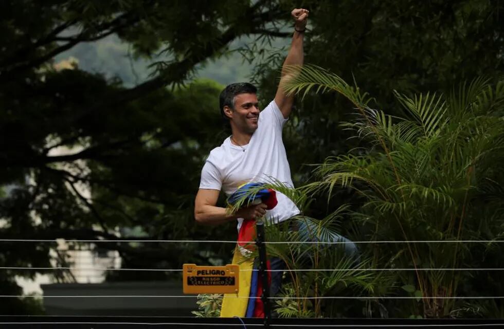 Opposition leader Leopoldo Lopez kisses a Venezuelan national flag as he greets supporters outside his home in Caracas, Venezuela, Saturday, July 8, 2017. Lopez was released from prison and placed under house arrest Saturday after more than three years in military lockup. Climbing atop a wall, Lopez briefly greeted a few dozen supporters gathered outside home. (AP Photo/Fernando Llano)