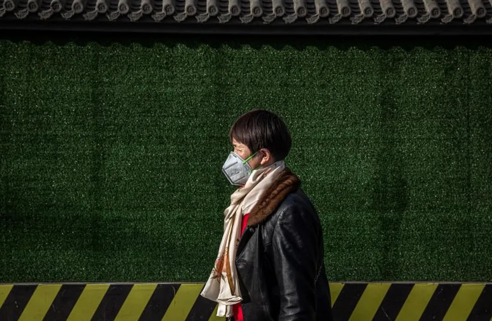 Beijing (China), 12/03/2020.- A woman wearing a protective face mask walks on the street in Beijing, China, 12 March 2020. Daily life in Beijing has been heavily affected by the coronavirus outbreak. The Covid-19 disease has so far killed at least 4,716 people and infected over 127,000 others worldwide. EFE/EPA/ROMAN PILIPEY