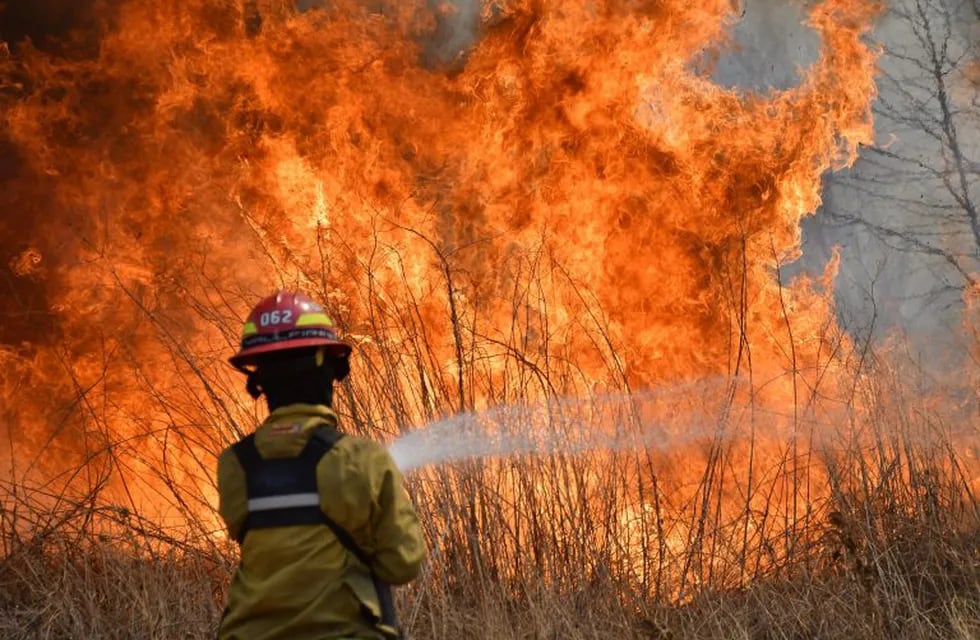 23 September 2020, Argentina, Cordoba: A firefighter douses flames of a wildfire near the Argentine National Observatory. Photo: Irma Montiel/telam/dpa