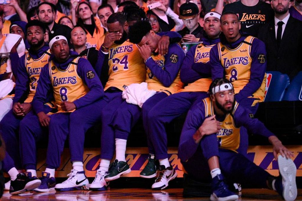 Los Angeles Lakers' LeBron James, center, and Quinn Cook wipe their faces while watching a video tribute to Kobe Bryant, before the Lakers' NBA basketball game against the Portland Trail Blazers in Los Angeles, Friday, Jan. 31, 2020. (AP Photo/Kelvin Kuo)