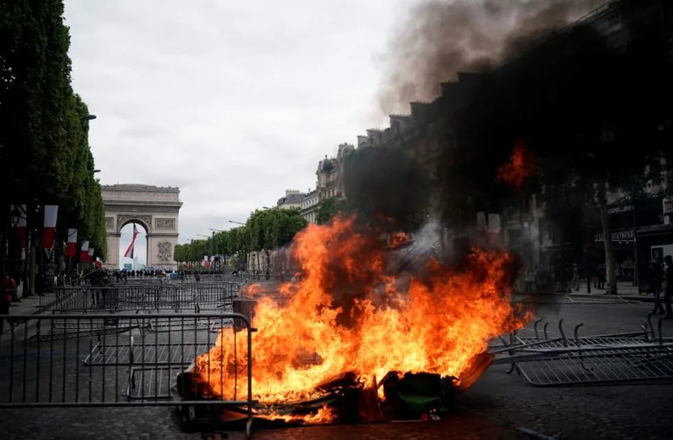 TOPSHOT - This picture taken on July 14, 2019 shows a fire in front of the Arc de Triomphe in Paris as protestors linked to the Yellow Vests (Gilets Jaunes) movement (unseen) take part in a demonstration on the side of the annual Bastille Day ceremony. (Photo by Kenzo TRIBOUILLARD / AFP)
