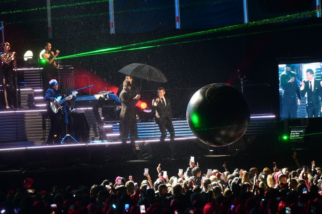 Una persona subió al escenario para cubrir al artista con un paraguas.