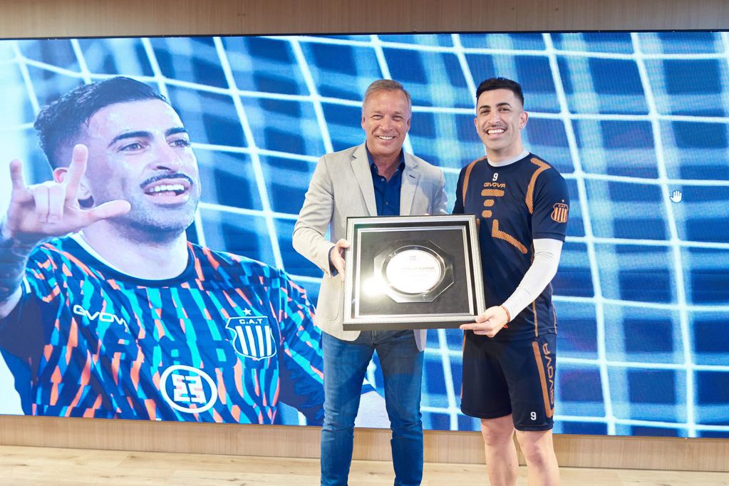 Andrés Fassi le entrega al uruguayo Michael Santos una plaqueta en reconocimiento a su exitoso paso por Talleres, a puro gol. (Prensa Talleres)