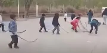 Niños de escuela practican hockey con ramas de palmera