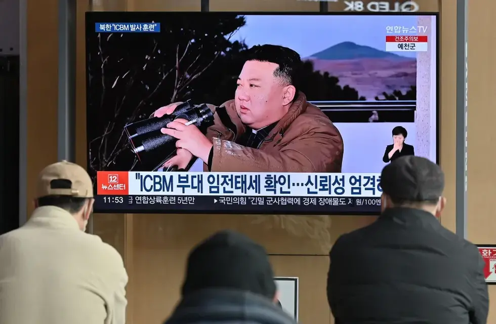 La gente ve una pantalla de noticias de televisión que muestra una imagen del líder de Corea del Norte, Kim Jong Un, presenciando el lanzamiento de prueba reciente de un misil balístico intercontinental.