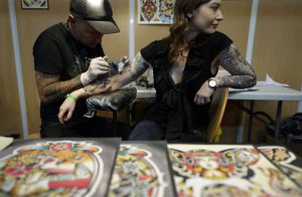 A tattooist works on a woman's arm during the first day of the second 