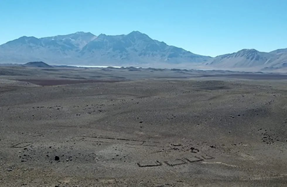 Una vista del sitio denominado LD-S25 que incluye estructuras de muros bajos de roca. Al fondo se puede observar la Laguna de Diamante.