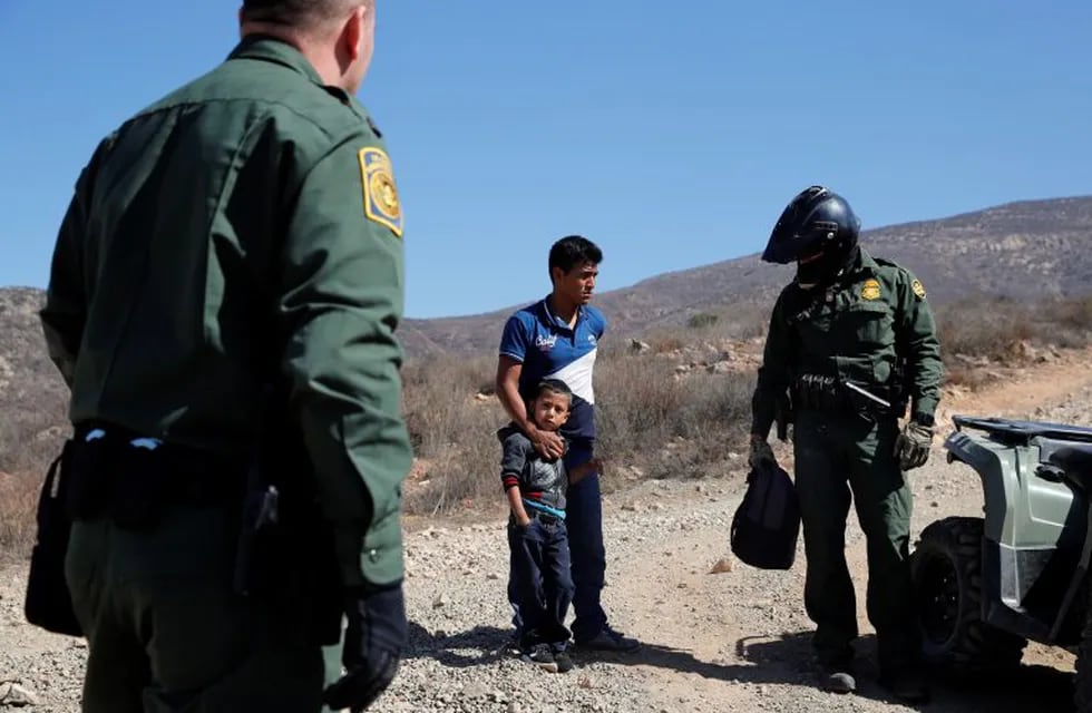 Un padre guatemalteco con su hijo cruzan la frontera entre México y Estados Unidos (AP)