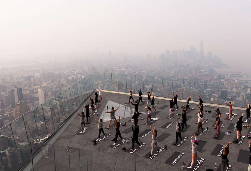 Personas asisten a una clase matutina de yoga en la plataforma de observación The Edge mientras una neblina causada por el humo de los incendios forestales que arden en Canadá se cierne sobre Manhattan en Nueva York. Foto: EFE/EPA/JUSTIN LANE