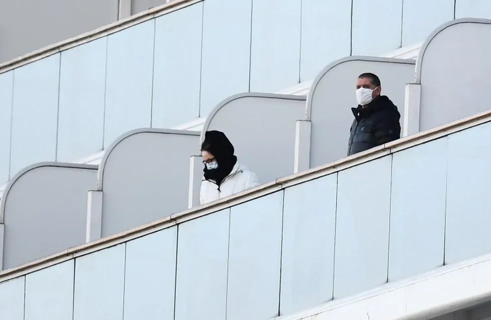 Passengers stand on balconies on the Diamond Princess cruise ship, with around 3,600 people quarantined onboard due to fears of the new coronavirus, at the Daikoku Pier Cruise Terminal in Yokohama port on February 10, 2020. - Around 60 more people on board the quarantined Diamond Princess cruise ship moored off Japan have been diagnosed with novel coronavirus, the country's national broadcaster said on February 10, raising the number of infected passengers and crew to around 130. (Photo by CHARLY TRIBALLEAU / AFP)