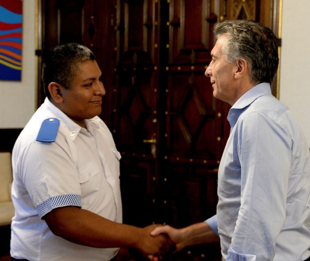 In this handout photo provided by the Argentine Presidency, released Thursday, Feb. 1, 2018, Argentine President Mauricio Macri, right, shakes hands with police officer Luis Chocobar at the presidential house in Buenos Aires, Argentina. Macri hailed Chocobar after the policeman shot a escaping robber on the back, raising fears that Macri's embrace will give the country's police force, with a long history of abuses, a green light to shoot first and ask questions later. (AP Photo/Argentine Presidency)