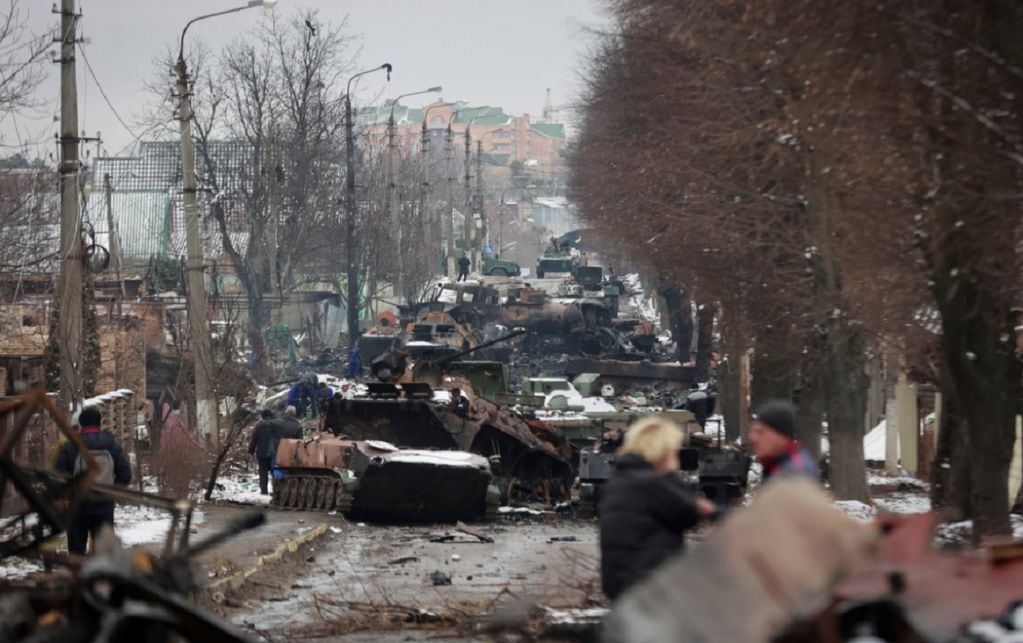 La gente mira los restos destripados de vehículos militares rusos en una carretera en la ciudad de Bucha, cerca de la capital, Kiev, Ucrania (AP)