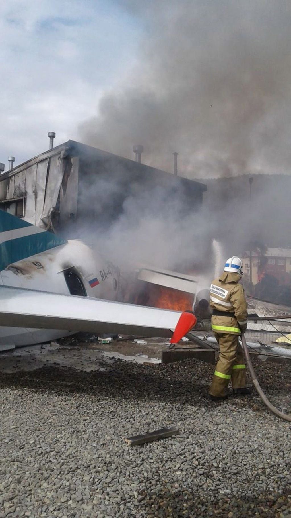 Los bomberos tratan de apagar las llamas tras estrellarse un avión de pasajeros en Nizhneangarsk, Rusia (EFE)