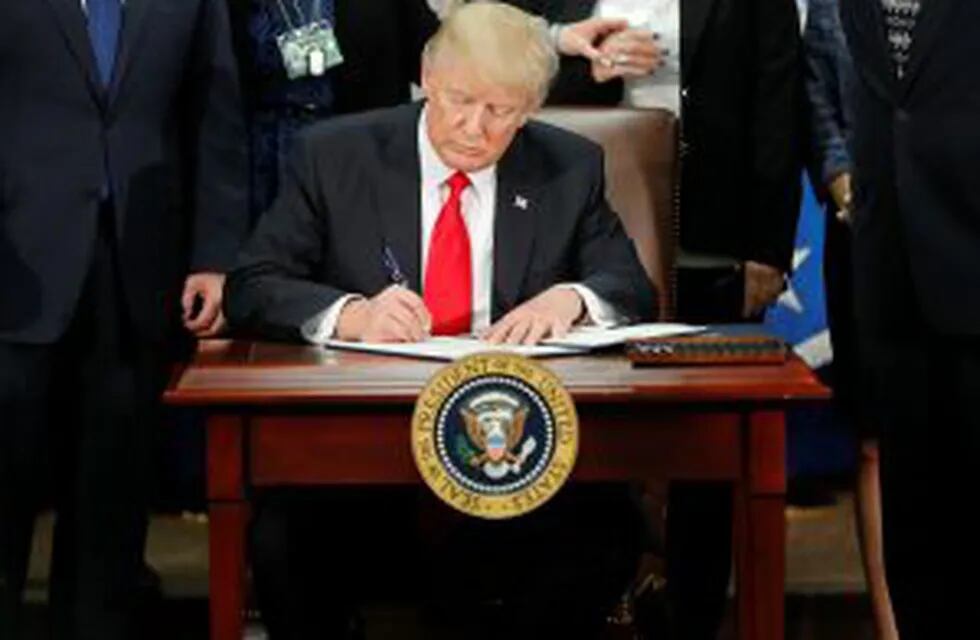 In this Jan. 25, 2017, photo, President Donald Trump signs an executive order for border security and immigration enforcement improvements at the Department of Homeland Security in Washington. Immigration to the United States has come in swells and dips o