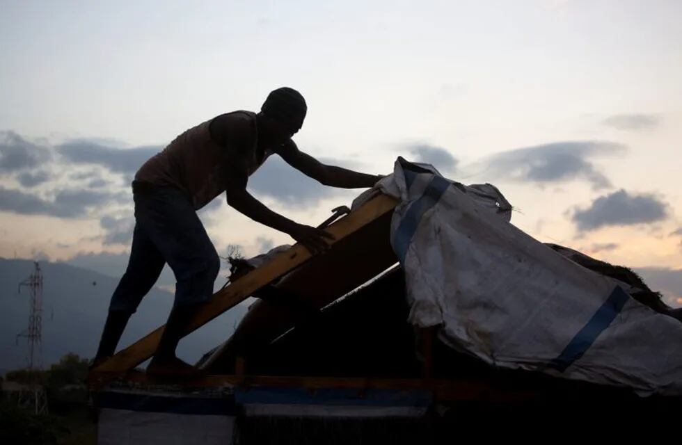 In this Dec. 2, 2016 photo, a man breaks downs his shelter in the Delmas tent camp set up nearly seven years ago for people displaced by the 2010 earthquake, in Port-au-Prince, Haiti. The man has agreed to resettle and move into a one-year rental provided