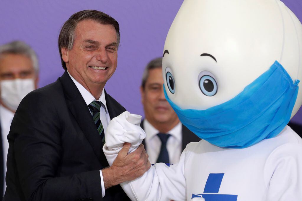 Contradicciones. Jair Bolsonaro posando con la mascota de la campaña de vacunación nacional, llamada "Ze Gotinha". (AP Photo / Eraldo Peres)