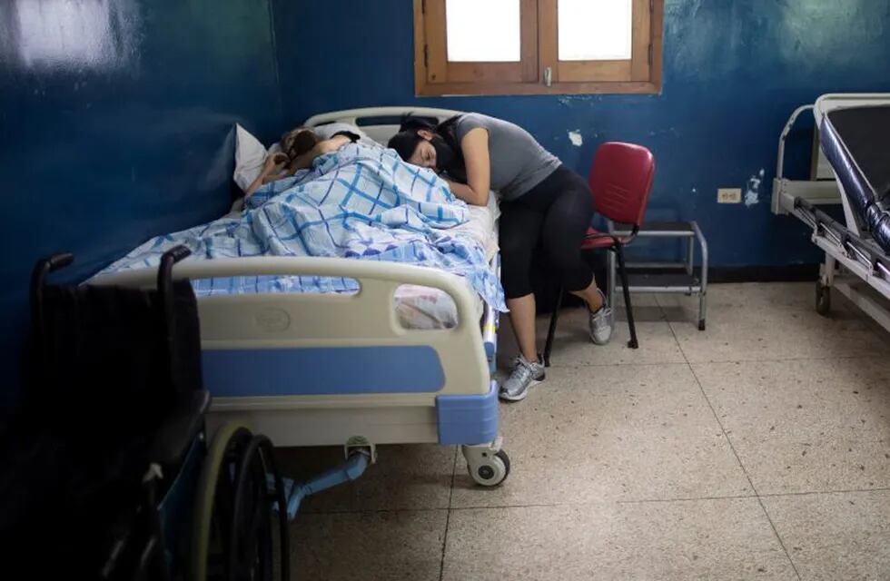 A woman leans on the side of a relative suffering cancer at the Luis Razetti Oncology hospital in Caracas, Venezuela, Wednesday, Sept 2, 2020. The hospital, which stopped admitting new cancer patients at the start of the mid-March lockdown to curb the spread of COVID-19, lacks water, air conditioning, supplies like lab materials, and even doctors, while only one of the five operating rooms is operational. (AP Photo/Ariana Cubillos)