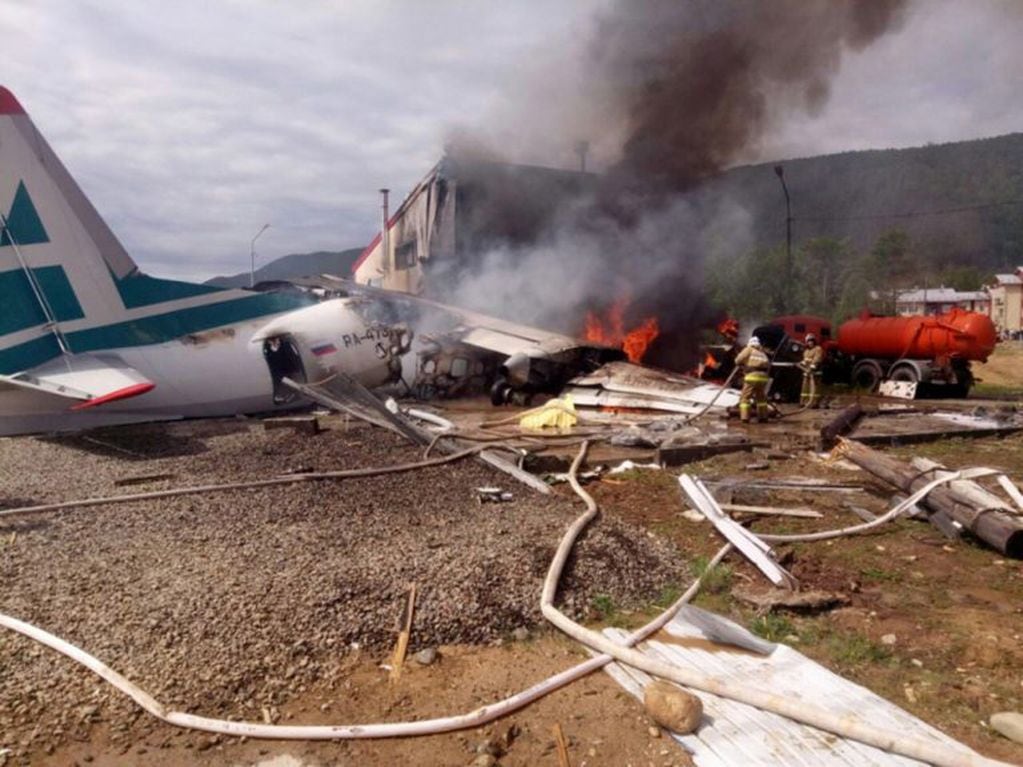 Los bomberos tratan de apagar las llamas tras estrellarse un avión de pasajeros en Nizhneangarsk, Rusia (EFE)