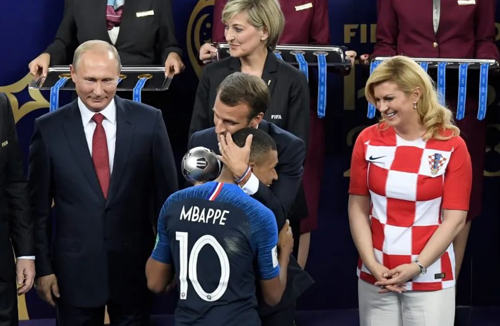 French President Emmanuel Macron (rear C) congratulates France's forward Kylian Mbappe (front C) as he receives the trophy for best young player next to Russian President Vladimir Putin (L) and Croatian President Kolinda Grabar-Kitarovic (R) during the trophy ceremony at the end of the Russia 2018 World Cup final football match between France and Croatia at the Luzhniki Stadium in Moscow on July 15, 2018. / AFP PHOTO / GABRIEL BOUYS / RESTRICTED TO EDITORIAL USE - NO MOBILE PUSH ALERTS/DOWNLOADS
