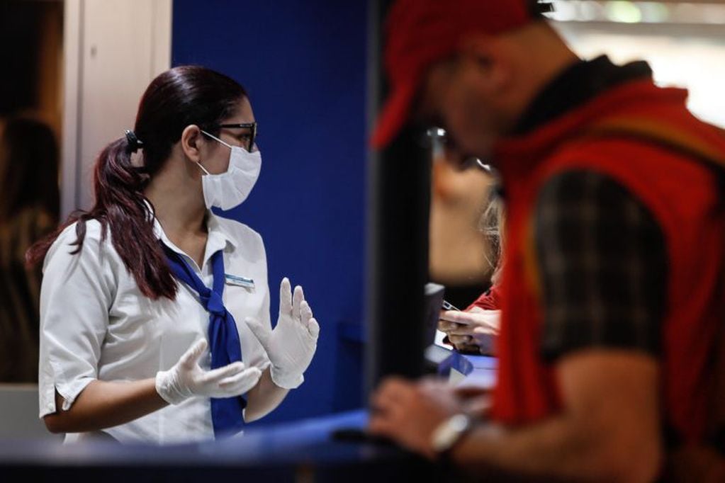 Pasajeros y empleados del Aeropuerto de Ezeiza se protegen con barbijos, tras la confirmación del primer caso de coronavirus en el país. (EFE)