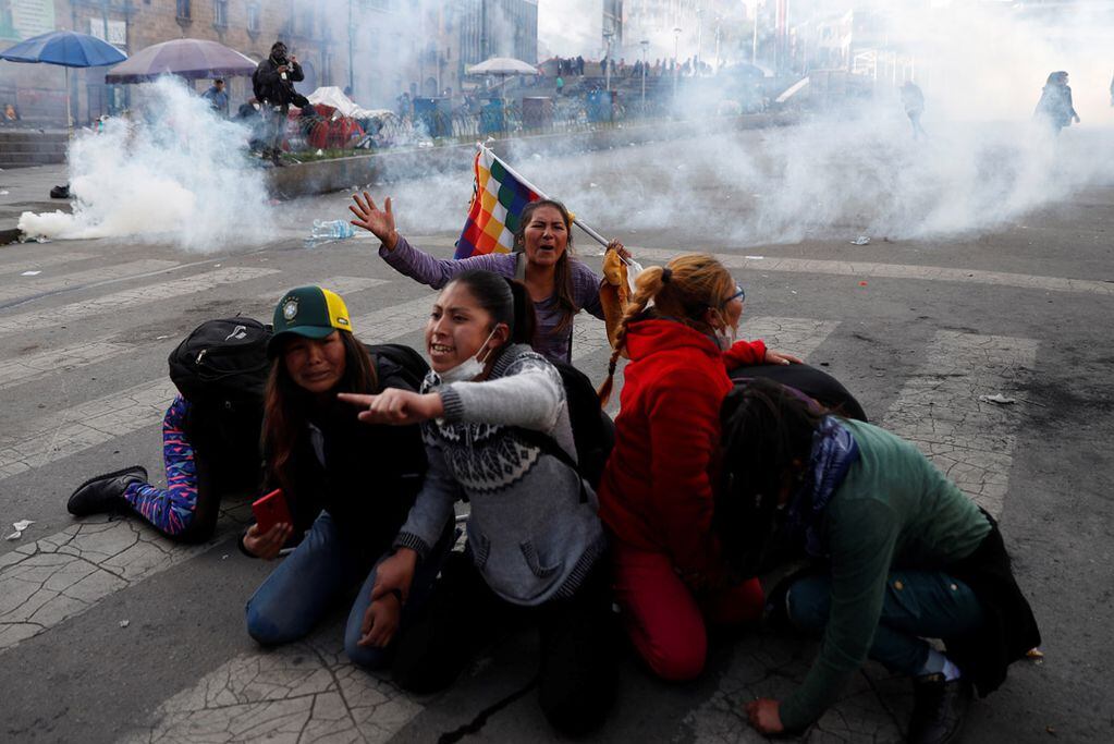 Partidarios del expresidente Evo Morales se protegen de los gases lacrimógenos lanzados por la policía en La Paz, Bolivia, el 15 de noviembre de 2019  (AP)