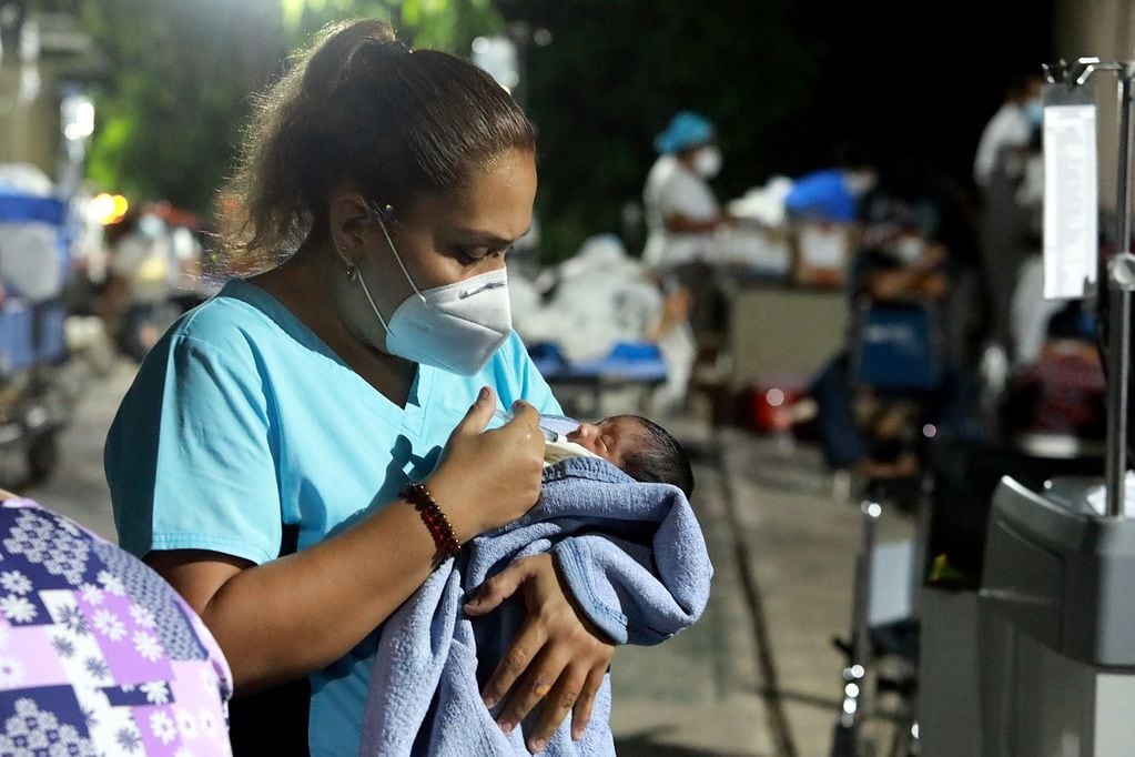 Una enfermera alimenta a un recién nacido en un hospital desalojado debido al terremoto.