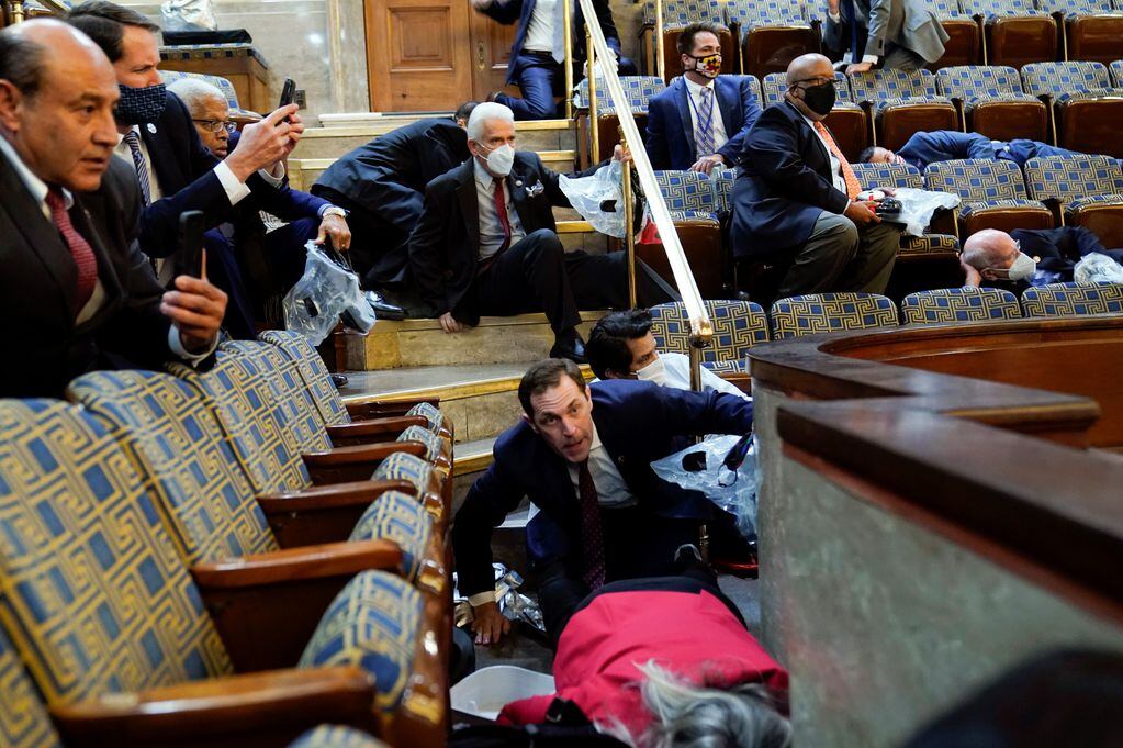 Las personas se refugian en la galería de la Cámara mientras los manifestantes intentan irrumpir en la Cámara de la Cámara en el Capitolio de los Estados Unidos.