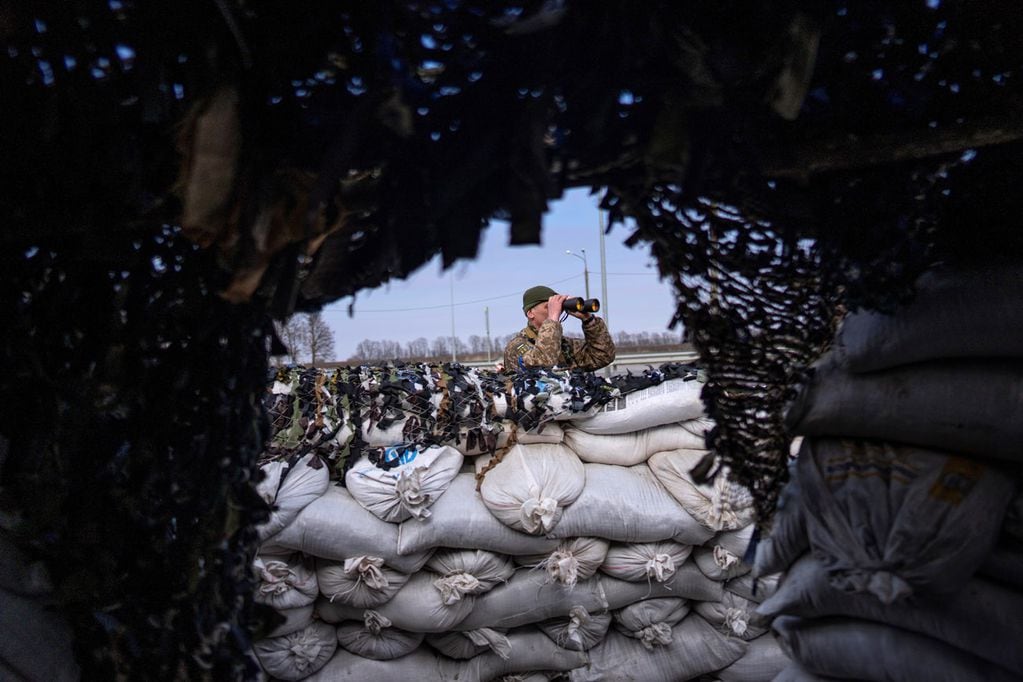 Un soldado ucraniano mira a través de binoculares en un puesto de control militar, en Lityn, Ucrania. (AP)