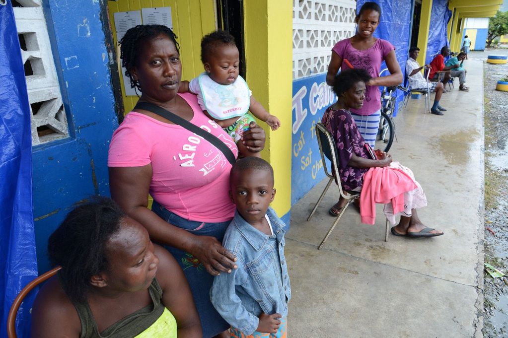 SHM12 - SAINT THOMAS (JAMAICA), 03/10/2016.- Mujeres con sus hijos esperan en la puerta de un refugio dispuesto en la escuela primaria Yallahs hoy, lunes 3 de octubre 2016, en Saint Thomas, Jamaica. El poderoso huracán de categoría 4 Matthew, con vientos 