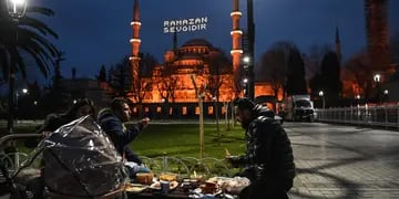 Muslims share Iftar, the evening fast-breaking meal on the first day of the Muslim fasting month of Ramadan at the Sultanahmet Square with the Blue mosque in background, in Istanbul on April 13, 2021. (Photo by Ozan KOSE / AFP)