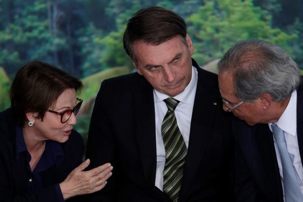 El presidente de Brasil, Jair Bolsonaro, en el centro, escucha a su ministro de Agricultura, Tereza Cristina, a la izquierda, y al ministro de Economía, Paulo Guedes. Crédito: AP Photo/Eraldo Peres.