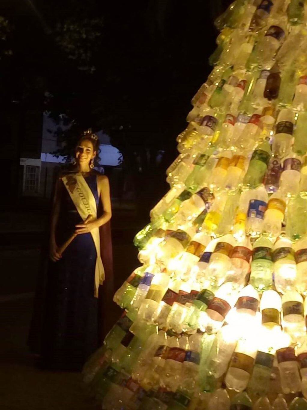La reina vendimial de Goudge, Romina Pérez, junto al árbol Navideño con botellas plásticas