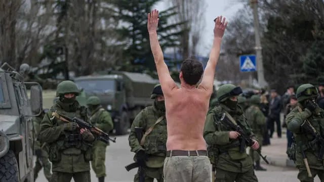 Sin bandera. Un ucraniano protesta frente a soldados rusos en Balaklava. Las tropas, sin embargo, no poseen elementos identificatorios, aunque por emblemas y patentes se sabe que son de la Federación (AP). 