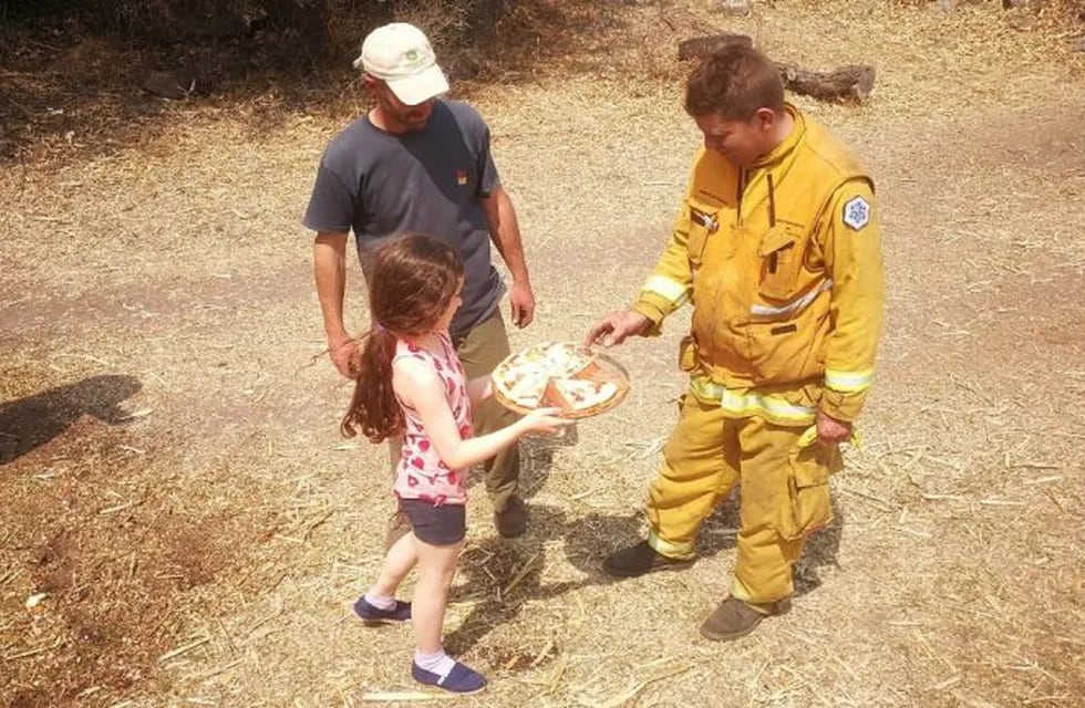 Emotivo gesto de una niña que le da pizza a bomberos voluntarios que trabajan en los incendios de Alpa Corral.
