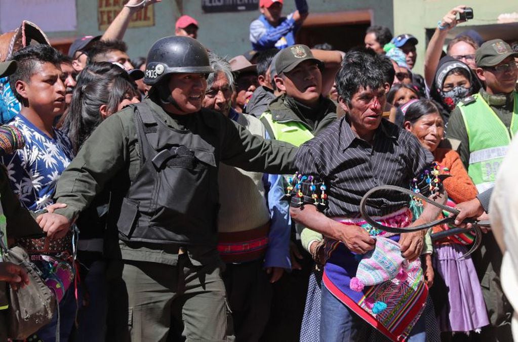 Un policía custodia el combate de dos Indígenas bolivianos de Potosí durante una tradicional pelea por la fiesta de la Cruz este sábado, en San Pedro de Macha. EFE/Martin Alipaz