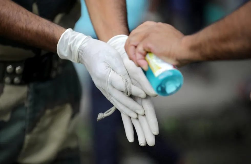 Kolkata (India), 15/07/2020.- Locals wearing protective gloves use a hand sanitizer after a coronavirus disease (COVID-19) test at a hospital in Kolkata, Eastern India, 15 July 2020. The Bengal goverment announced that the ongoing lockdown will continue until 31 July, in 'containment zones.' The restrictions will be eased in a phased manner with places of worship, hospitality services and shopping malls scheduled to be opened in the initial phase with restrictions. The areas termed as 'containment zones' will be identified by authorities and those areas will remain under complete lockdown. (Abierto) EFE/EPA/PIYAL ADHIKARY