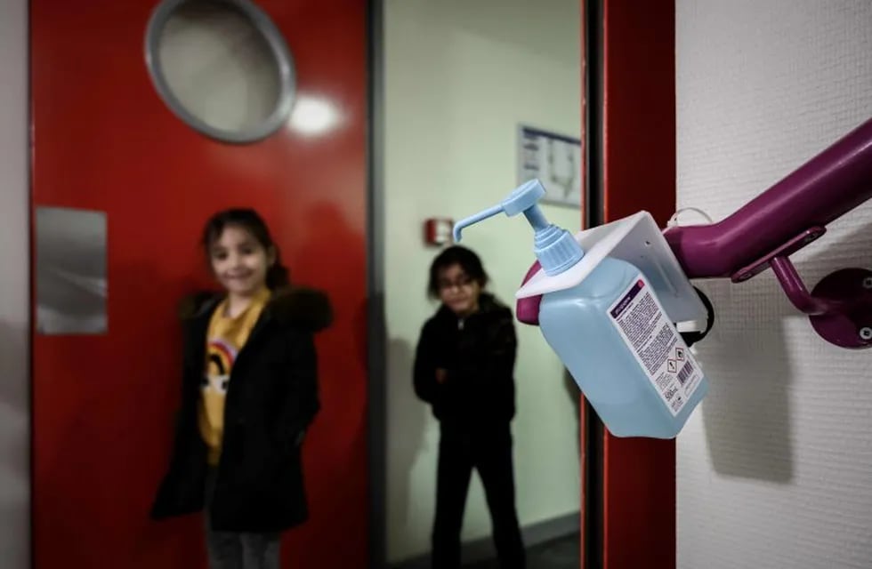 Los niños se desinfectan las manos con alcohol en gel antes de entrar al aula. (Foto: AFP)