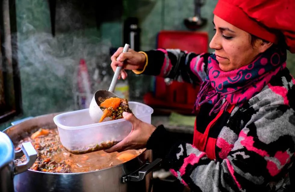 A woman serves food at a soup kitchen which feeds at least 200 people hit hard by the economic crisis, at the Villa 21-24 shantytown in Buenos Aires on September 3, 2019. - After the bank run occured Monday with a depreciation of the peso of over 20%, price hikes are expected to impact Argentinians' pockets again. (Photo by RONALDO SCHEMIDT / AFP)  POBREZA EMERGENCIA ALIMENTARIA - ALIMENTOS COMIDA  VILLA 21 24