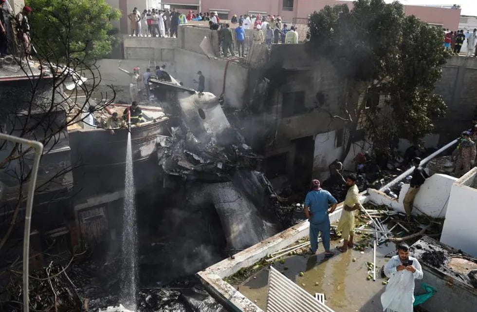TOPSHOT - Firefighters spray water on the wreckage of a Pakistan International Airlines aircraft after it crashed at a residential area in Karachi on May 22, 2020. - A Pakistani passenger plane with nearly 100 people on board crashed into a residential area of the southern city of Karachi on May 22. (Photo by Rizwan TABASSUM / AFP)