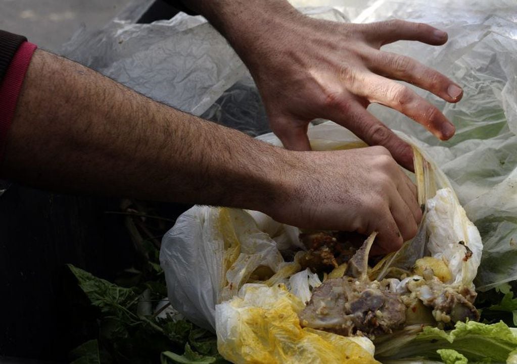 Un hombre buscando alimentos comida en la basura (AFP/Alejandro PAGNI)