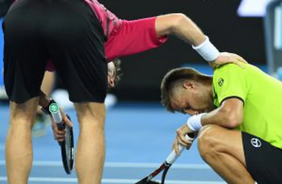 an Wawrinka of Switzerland consoles Martin Klizan of Slovakia (R) after winning the men's singles first round match on day one of the Australian Open tennis tournament in Melbourne on January 16, 2017.  / AFP PHOTO / WILLIAM WEST / --IMAGE RESTRICTED TO EDITORIAL USE - STRICTLY NO COMMERCIAL USE--