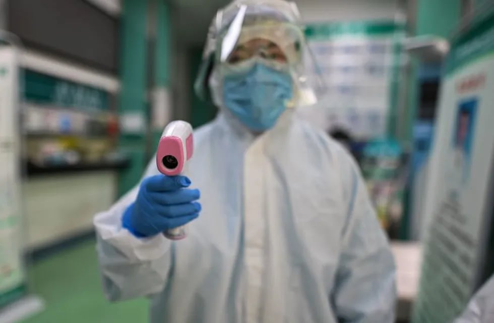 TOPSHOT - A medical worker prepares to check the temperature of an AFP photojournalist before a COVID-19 coronavirus test in Wuhan in China's central Hubei province on April 16, 2020. - China has largely brought the coronavirus under control within its borders since the outbreak first emerged in the city of Wuhan late last year. (Photo by Hector RETAMAL / AFP)