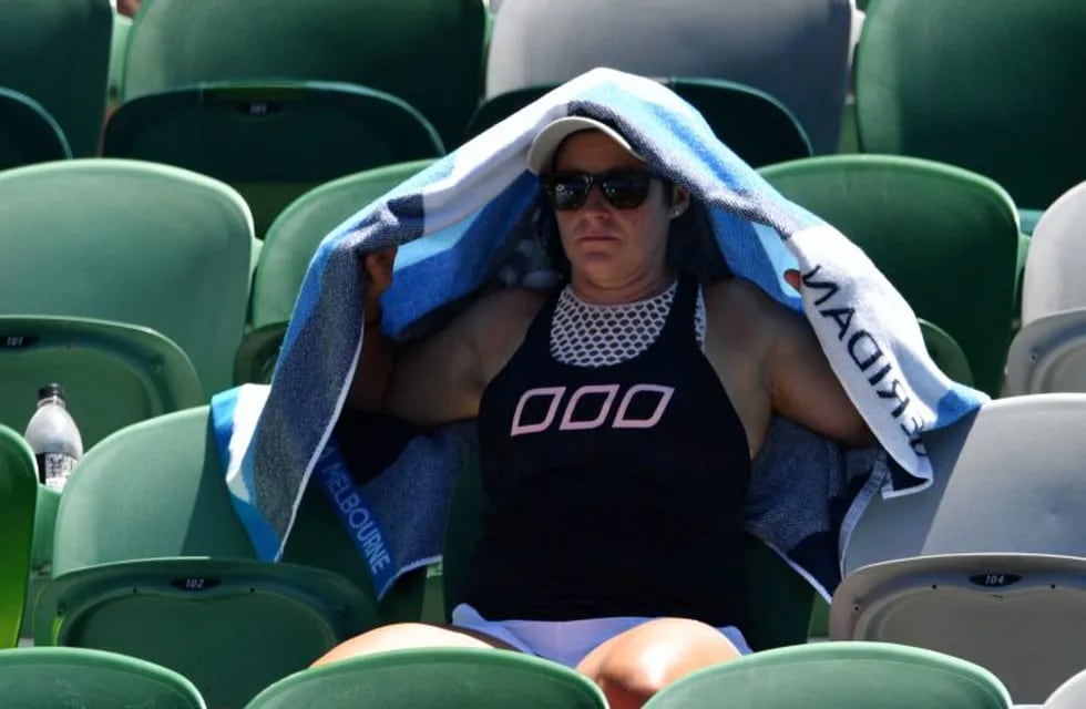 Un espectador se resguarda del sol en plena tribuna de uno de los estadios del Australian Open. / AFP PHOTO / SAEED KHAN /