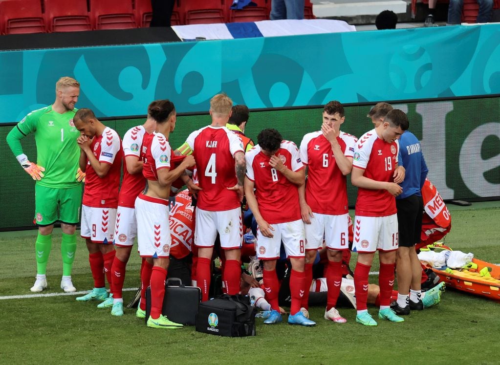 Futbolistas de Dinamarca rodean a su compañero Christian Eriksen, quien se desvaneció en pleno partido ante Finlandia por la Euro 2021.