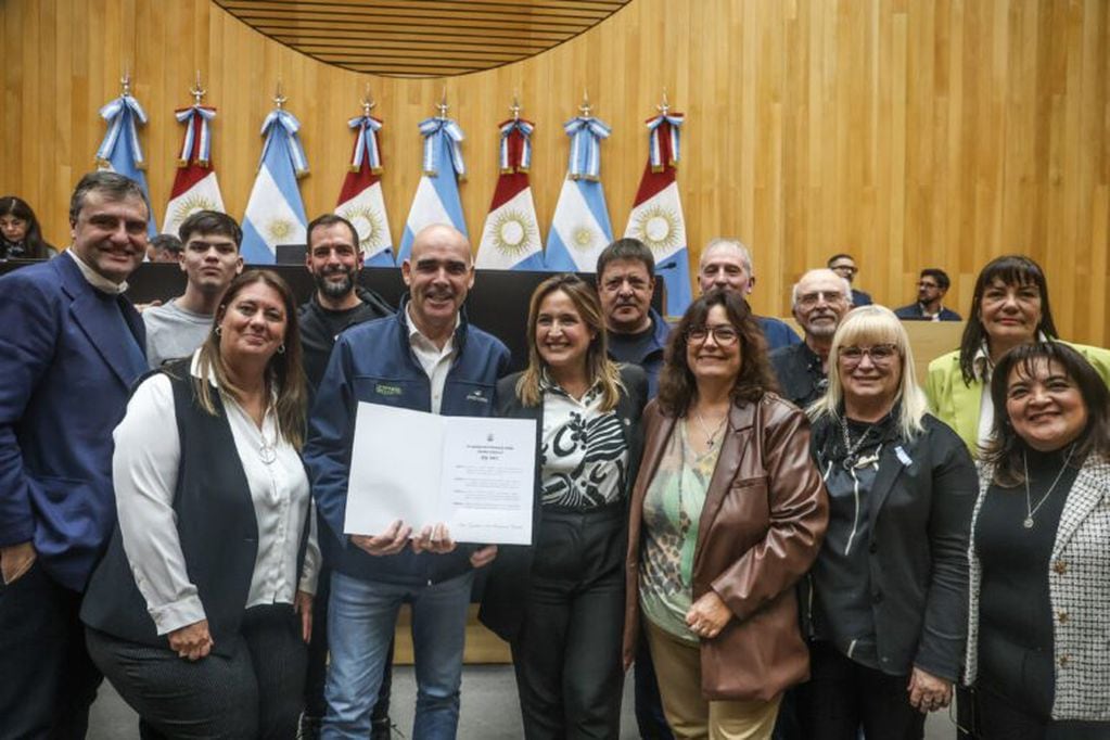 Gustavo Beccaría, promotor de Rally Cordobés, exhibe la distinción de la Legislatura, junto a Mungi, legisladores y pilotos; entre ellos, Gabriel Pozzo.