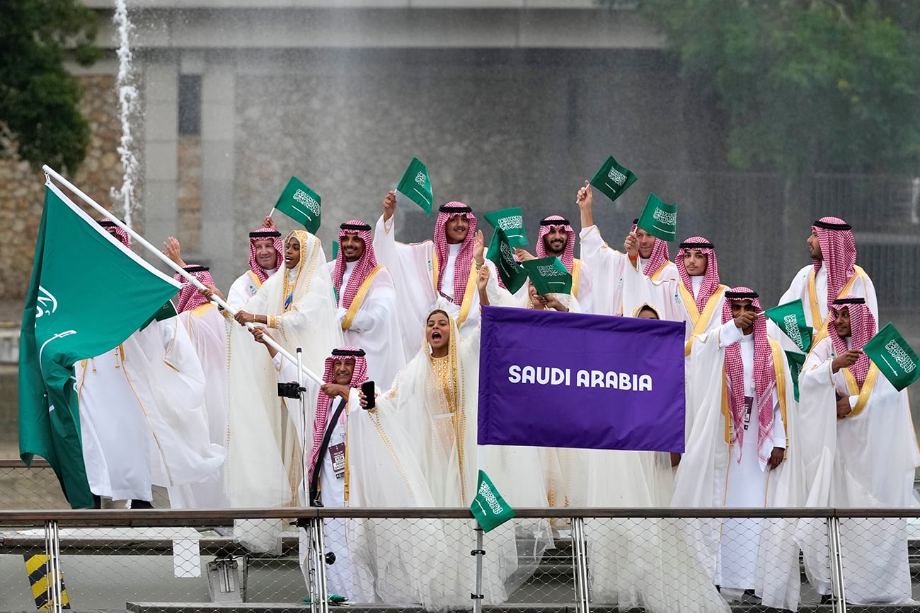 El equipo de Arabia Saudita ondea banderas en un barco en París, Francia, durante la ceremonia de apertura de los Juegos Olímpicos de Verano de 2024, el viernes 26 de julio de 2024. (Foto AP/Kirsty Wigglesworth)