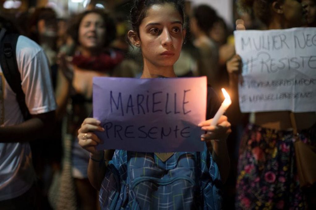 A woman holds a sign that reads in Portuguese "Marielle present," during a protest against the murder of councilwoman Marielle Franco in Rio de Janeiro, Brazil, Friday, March 16, 2018. Franco was slain Wednesday night while returning from an event focused on empowering young black women. (AP Photo/Leo Correa)