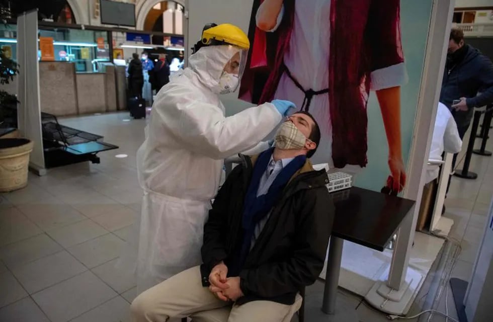 A health worker collects a nasal swab sample from a passenger to be tested for COVID-19 before he is allowed to board a ferry to Buenos Aires, at Argentinian ferry service company Buquebus' terminal in the port of Montevideo, on July 10, 2020. - Technicians of the Technological Laboratory of Uruguay (LATU) set up a floating laboratory on a ferryboat of Buquebus -the only liner linking the capitals- after the polemic entry to Uruguay of two Argentinian citizens infected with COVID-19 in June. The Uruguayan government of President Luis Lacalle Pou requires since Monday that travellers from abroad have a negative test for the new coronavirus done within 72 hours before the trip and another one seven days after, since flights from Europe were resumed. (Photo by Pablo PORCIUNCULA / AFP)