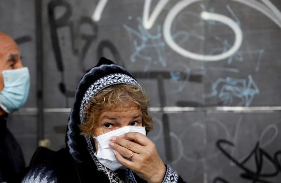 A woman, wearing a protective face mask, waits in line outside a bank during a government-ordered lockdown to curb the spread of the new coronavirus, in Buenos Aires, Argentina, Saturday, April 4, 2020. The city banks are opening for the weekend so that retirees may pick up their monthly pension payment. (AP Photo/Natacha Pisarenko)