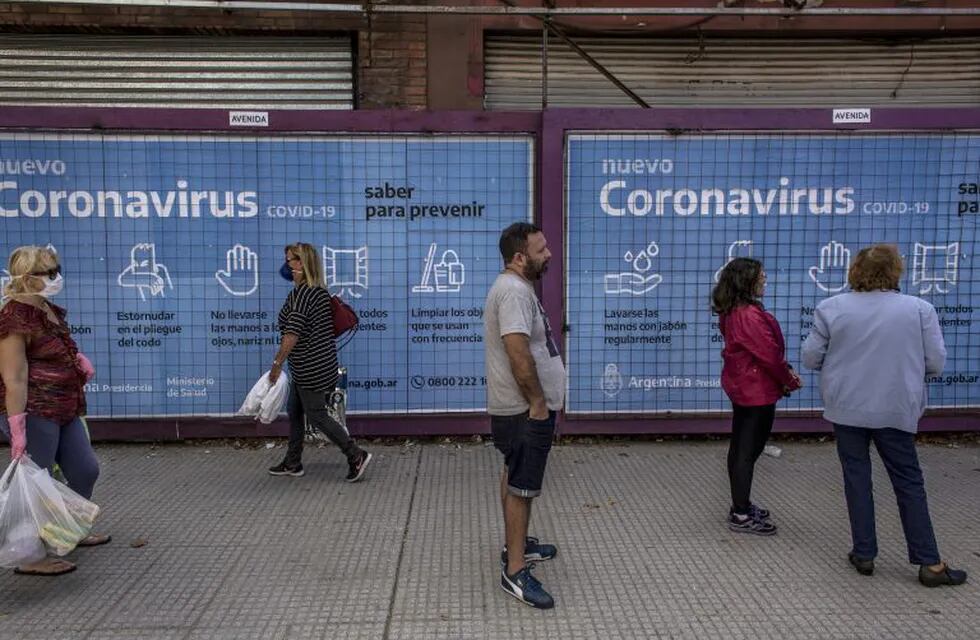 People line up for Banco de la Nacion in front of a Coronavirus sign in Buenos Aires, Argentina, on Friday, April 3, 2020. Thousands of pensioners and citizens who have government assistance, lined up outside banks to receive their monthly payments. Branches, which have been closed since a nationwide lockdown began March 20, reopened Friday so that citizens who can’t receive the payments on debit could receive the cash. Photographer: Sarah Pabst/Bloomberg
